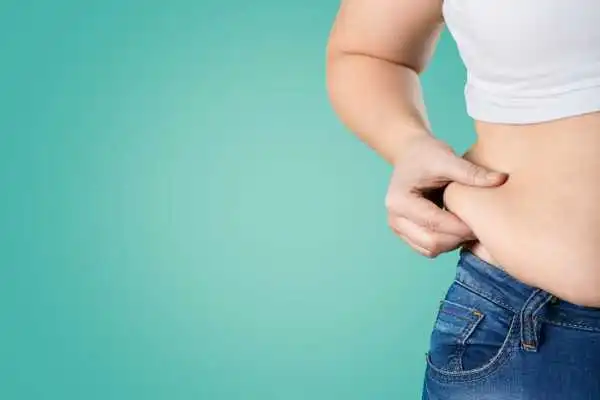 Image of woman pinching her love handles to show weight gain Devizes
